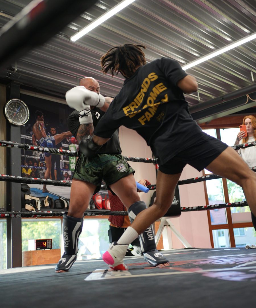 Een kickbokser in de ring, midden in een trap