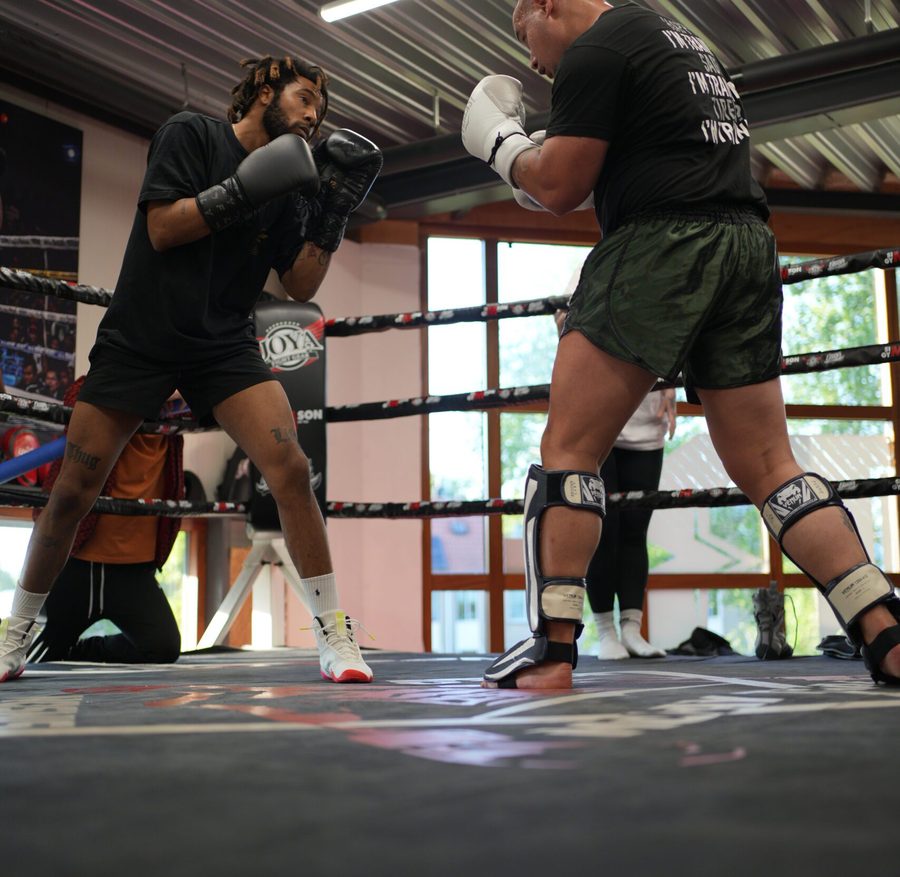 Twee sporters sparren in de ring met scheenbeschermers