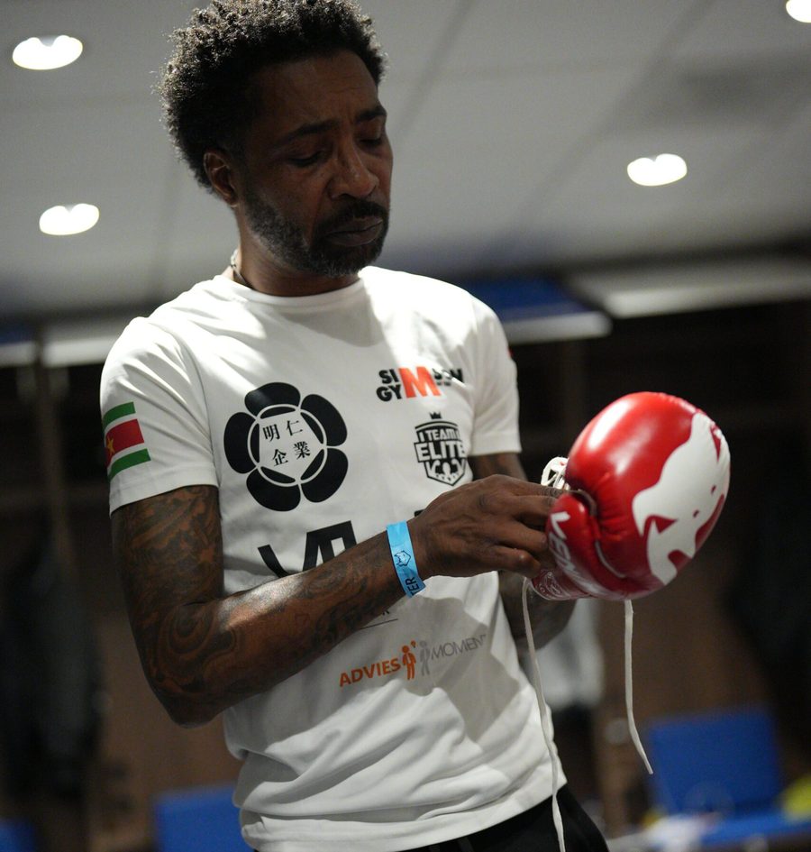 Een trainer in wit shirt maakt een rode bokshandschoen vast